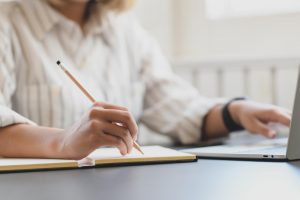 Una mujer tomando notas que lee en una notebook